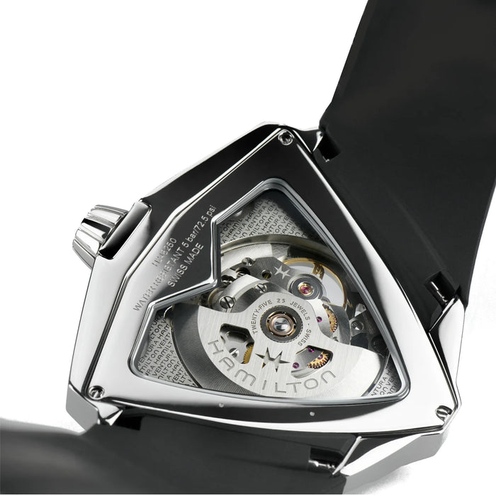 Close-up of the back of a Hamilton watch with a polished silver-tone case, transparent window, and visible automatic mechanical movement, attached to a black strap on a white background.