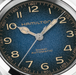 Close-up of a Hamilton Khaki Automatic watch dial with a textured blue gradient face, cream Arabic numerals, and matching cream hands.