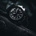 Black wristwatch with detailed face on a dark background