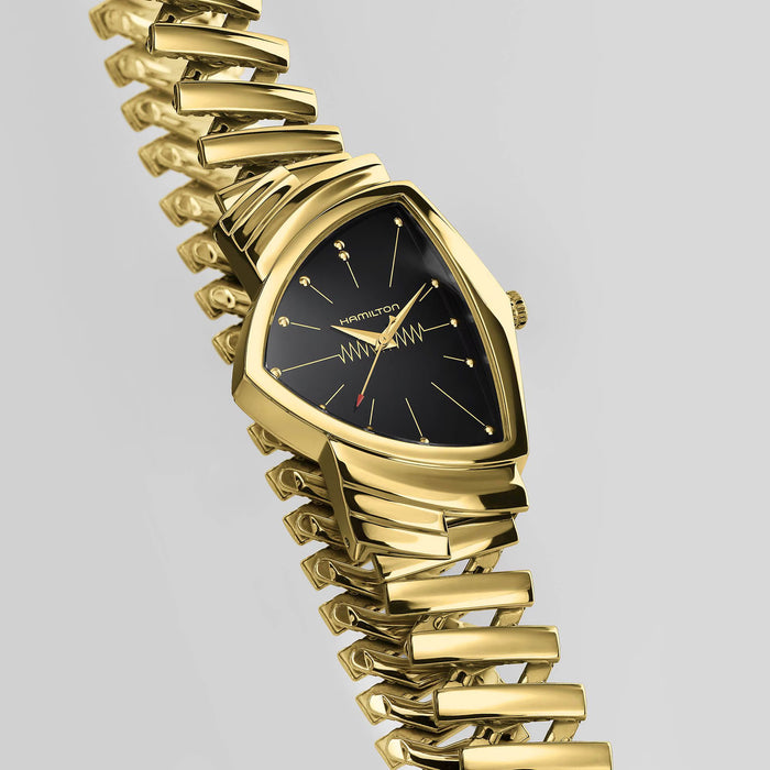 Gold wristwatch with a black face on a gray background