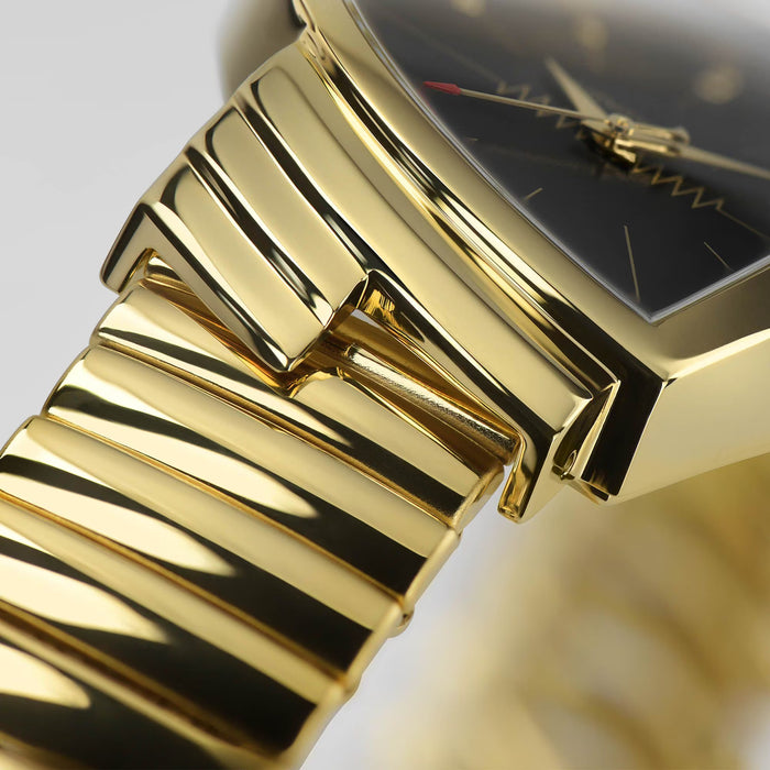 Gold wristwatch with a close-up of the band on a blurred background