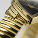 Gold wristwatch with a close-up of the band on a blurred background