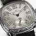 Hamilton watch with a silver sunburst dial, black Arabic numerals, a small seconds subdial, and an engraved silver-tone case on a black leather strap.