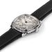 A close-up of a Cartier watch with a silver-toned shield-shaped dial, black Arabic numerals, and a black leather strap on a white background.