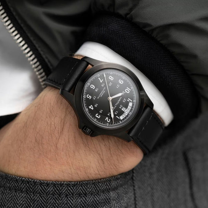 Black wristwatch on a person's wrist with a blurred background
