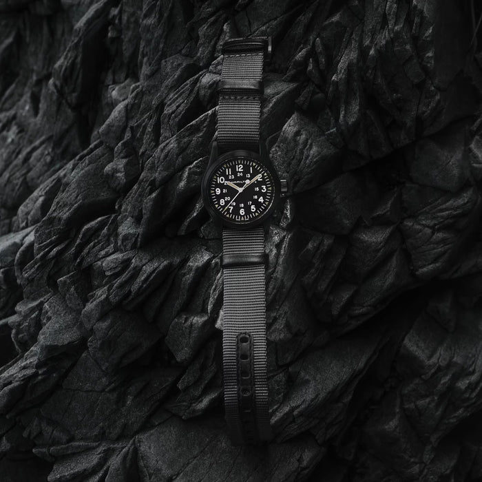 Black watch with mesh band on a textured black surface