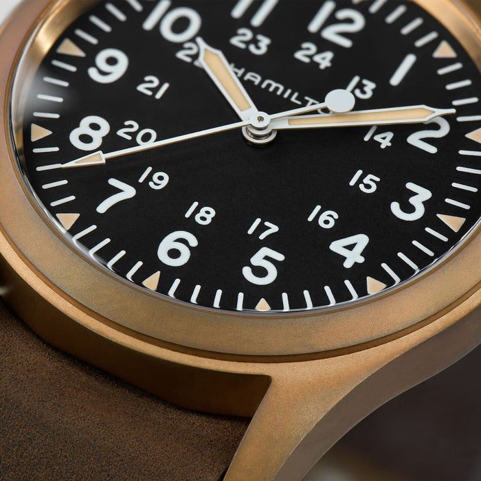 Close-up of a Hamilton watch with a black dial and gold casing.