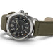 Wristwatch with olive green strap and black dial on a white background