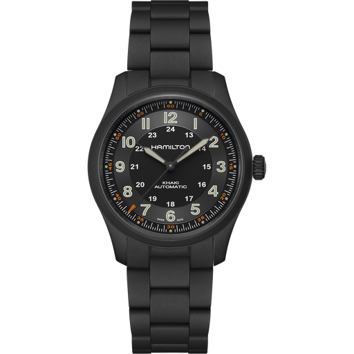 A Hamilton Kilian Automatic watch with a matte black case and integrated link bracelet, featuring a black dial with luminous beige numerals and hands, and orange accent markers.
