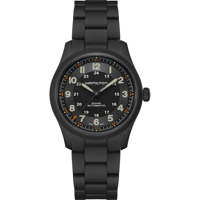 A Hamilton Kilian Automatic watch with a matte black case and integrated link bracelet, featuring a black dial with luminous beige numerals and hands, and orange accent markers.