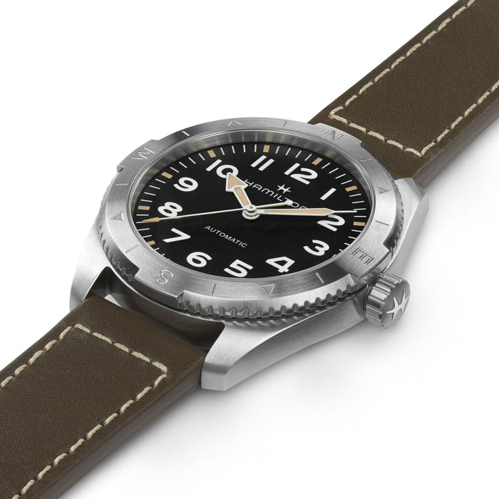 Watch with brown leather strap and black dial on a white background