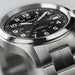 Hamilton watch with black dial and silver metal bracelet on a light gray background