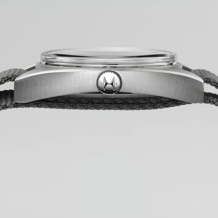 Close-up of a watch with a metallic case and black strap on a light gray background