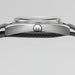 Close-up of a watch with a metallic case and black strap on a light gray background