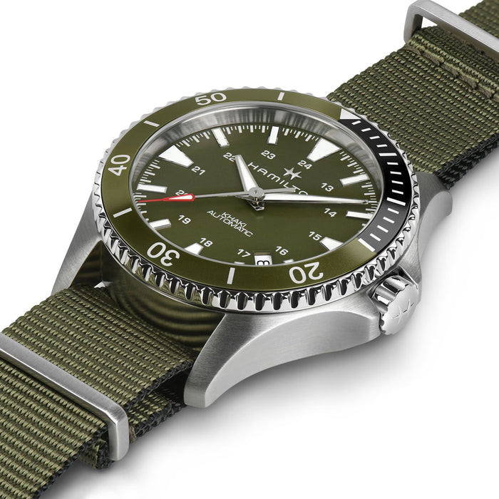 Hamilton watch with an olive green dial and matching green nylon strap, featuring a silver stainless steel case and a black rotating bezel.