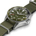 Hamilton watch with an olive green dial and matching green nylon strap, featuring a silver stainless steel case and a black rotating bezel.