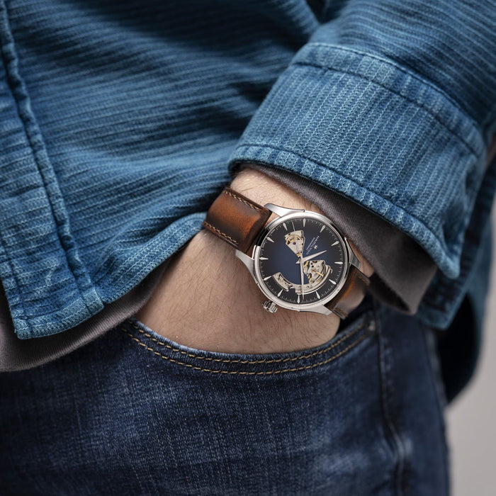 Close-up of a wrist wearing a watch with a detailed face, against a blurred background.
